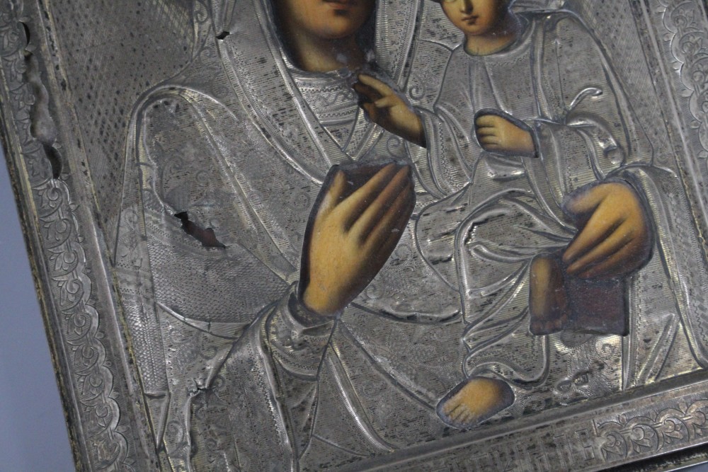 A Russian white metal overlaid tempera on panel icon, depicting the Virgin Mary and Christ child, 22 x 18cm